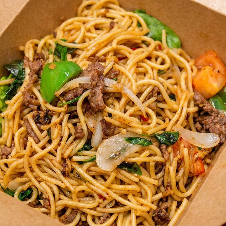 Spicy beef noodles with vegetables in a brown takeout box.